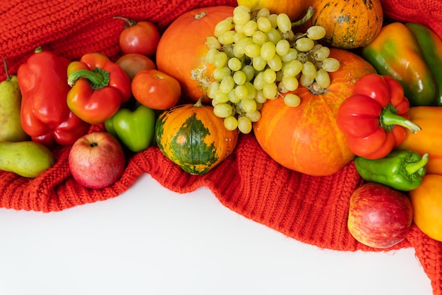 Thanksgiving Day. Big autumn harvest - pear, apples, pumpkin, pepper, tomato on a white background and red cloth. Thanksgiving celebration concept, top view.