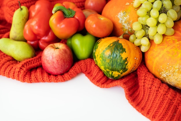 День Благодарения. Большой осенний урожай - груша, яблоки, тыква, перец, помидор на белом фоне и красной ткани. Концепция празднования благодарения.