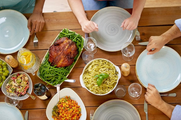 Thanksgiving day eating and leisure concept group of people having roast chicken or turkey and pasta for dinner at table with food