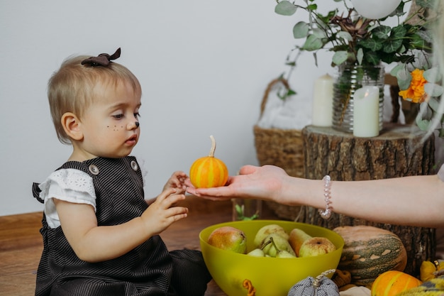 Thanksgiving groeten thanksgiving met familie thuis schattige baby peuter meisje spelen met pompoenen