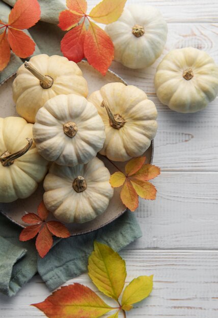 Thanksgiving season still life with small pumpkins and fall leaves over rustic wooden background