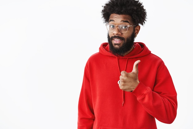 That is good content Portrait of satisfied goodlooking african american music producer with beard in glasses and red hoodie showing thumb up raising eyebrows and smiling assured in like product