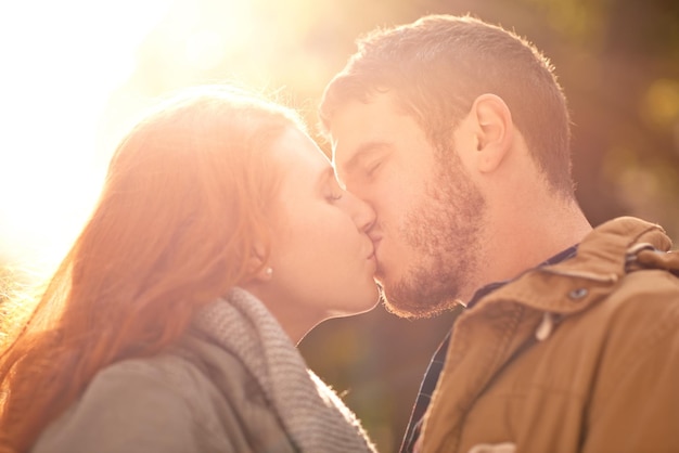 あなたの魂を照らすそのキス屋外でキスを共有する幸せな若いカップルのショット