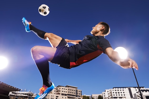 写真 そのテクニックは、空中でボールを蹴る若いサッカー選手の完璧なショットです