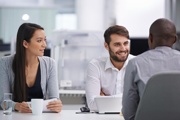 Thats his Friday smile Three happy coworkers sitting down to have a meeting