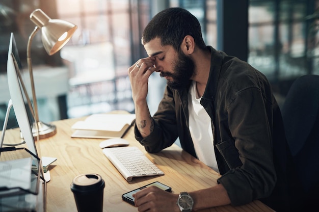 Foto ecco fatto. inquadratura di un giovane uomo d'affari che si sente stressato mentre lavora a tarda notte in un ufficio moderno