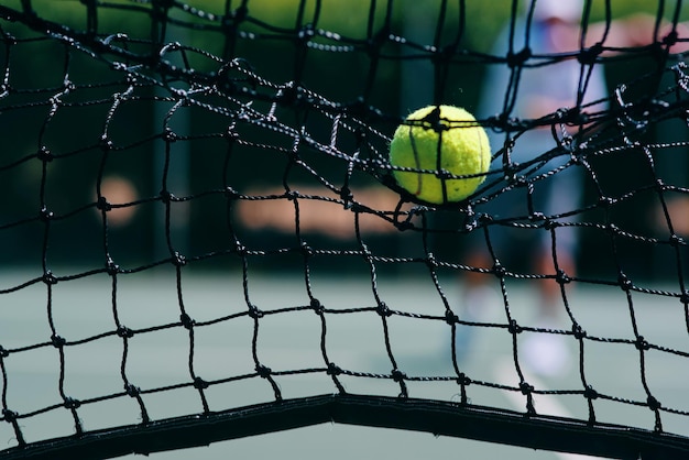 Это потерянное очко. Обрезанный снимок теннисного мяча, ударившегося о теннисную сетку на корте днем.
