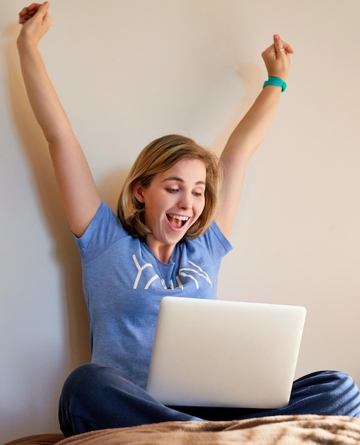 Foto questo è un nuovo record inquadratura di una giovane donna felice che reagisce a qualcosa di eccitante sul suo laptop a casa