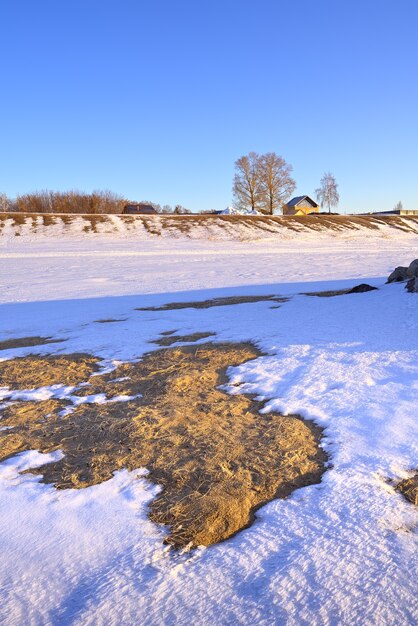 Thawing on the shore of the Ob Sea A snowy spring riverbank a yellow house