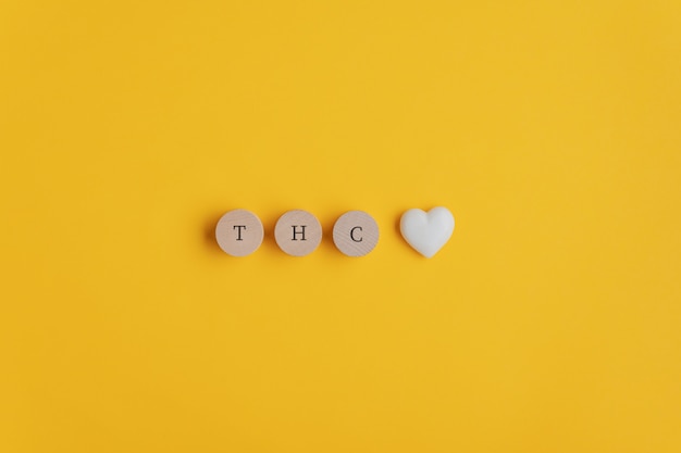 Thc spelled on wooden cut circles with heart shaped marble at the end