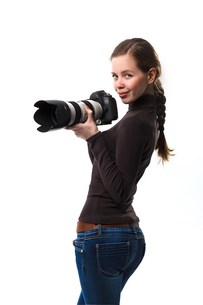 사진 스튜디오에서 흰색 배경에 포즈를 취하는 전문 dslr 카메라를 가진 아름다운 사진작가 소녀
