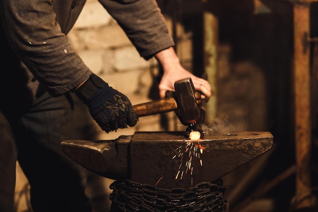 写真 鍛冶屋は火花花火で鍛冶屋の金床に赤熱した金属を手動で鍛造します。