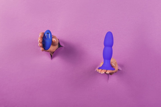 Фото Синяя силиконовая секс-игрушка с пультом на розовом фоне в руках женщины