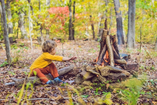 写真 少年はキャンプの火に座っています