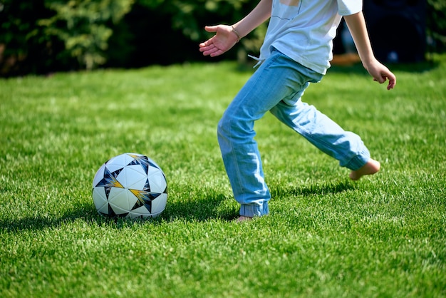 写真 少年は靴なしで芝生の上でサッカーボールを走る