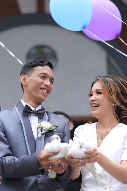Фото Невеста и жених носят пару голубей и воздушных шаров
