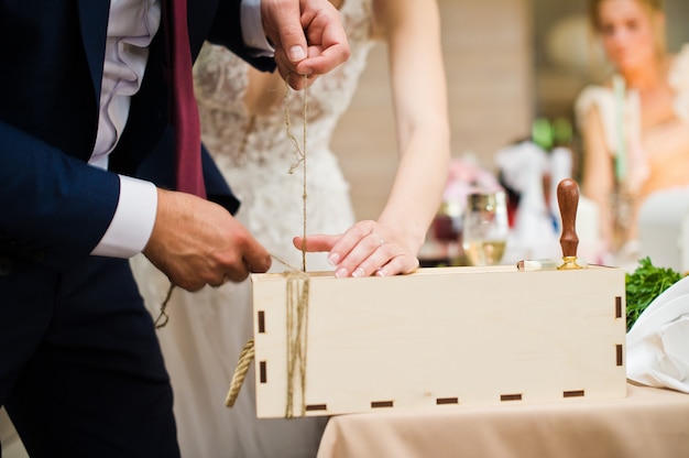 Жених и невеста запечатывают бутылку вина на свадебном банкете.