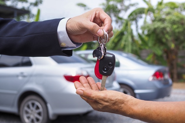 写真 車のセールスマンは、新しい車の所有者にキーを送りました。レンタルコンセプトの売買