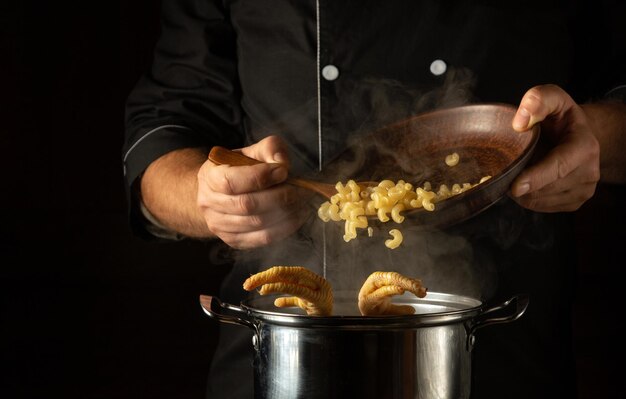 写真 料理人は沸騰しているの足の鍋にパスタを加えレストランやホテルのキッチンで美味しいスープを準備するコンセプト