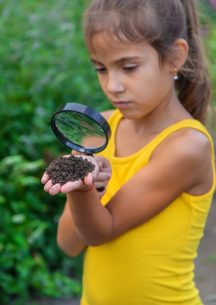Фото Ребенок рассматривает землю в лупу. выборочный фокус.