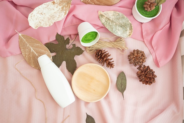 Фото Композиция отображает товар. белая косметическая бутылка с декором из натуральных сушеных листьев. минималистичная композиция из продуктов