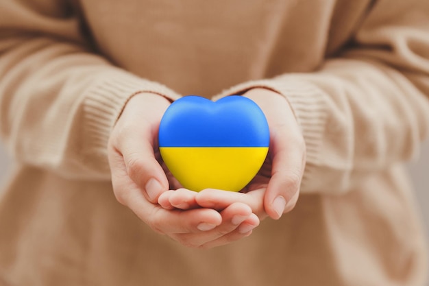 Фото Концепция прекращения войны в украине женские руки держат флаг украины с нарисованным сердцем семья