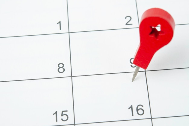 写真 カレンダーの日付に画鋲を使用した計画と期限の概念
