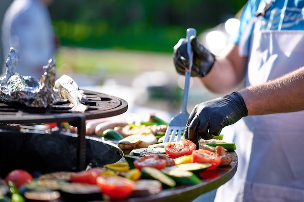 写真 料理人は夏にグリルで野菜と肉を準備します