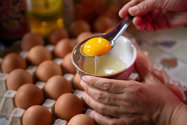 写真 コックは調理用のスプーンで卵の卵黄を分離します