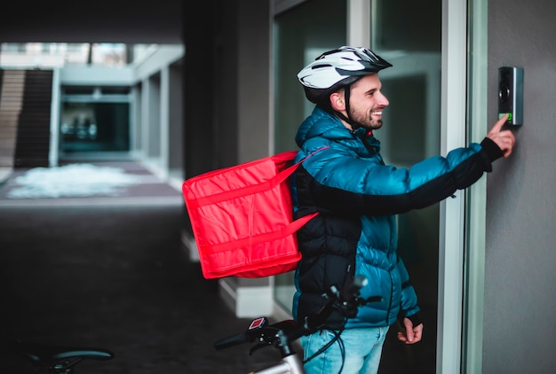 写真 自転車を持った宅配便が家の呼び鈴を鳴らして食べ物を届けます。温かい料理、宅配、ベルを鳴らします。