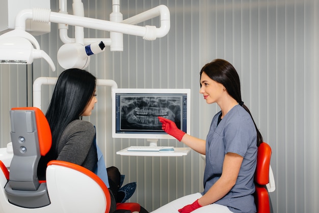 Стоматолог показывает фотографию зубов пациента и рассказывает о необходимом лечении. стоматология, здоровье.