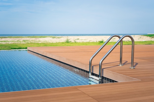 The edge Luxe zwembad met trap en houten vlonder bij hotel aan het strand.