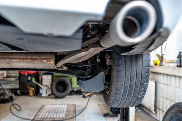 写真 車の下から見た車の排気システムは車のワークショップのエレベーターにあります