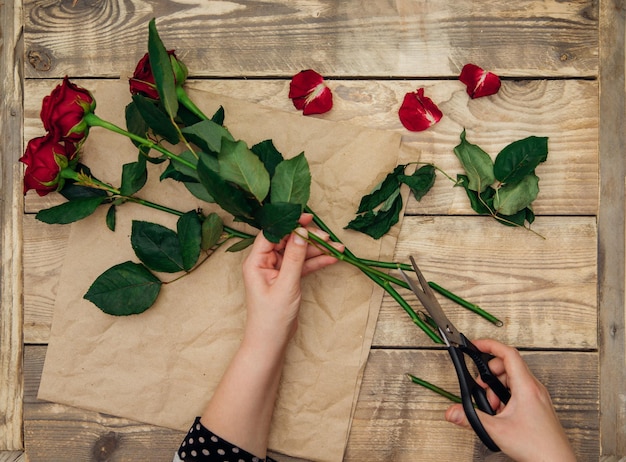 写真 花屋はバラのフラワーアレンジメントを作成し、女性の手ははさみで茎を切ります。お祭り気分。