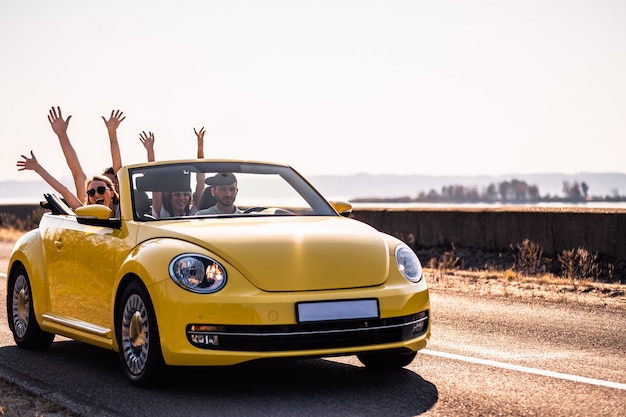 Фото Четверо друзей едут в желтом кабриолете