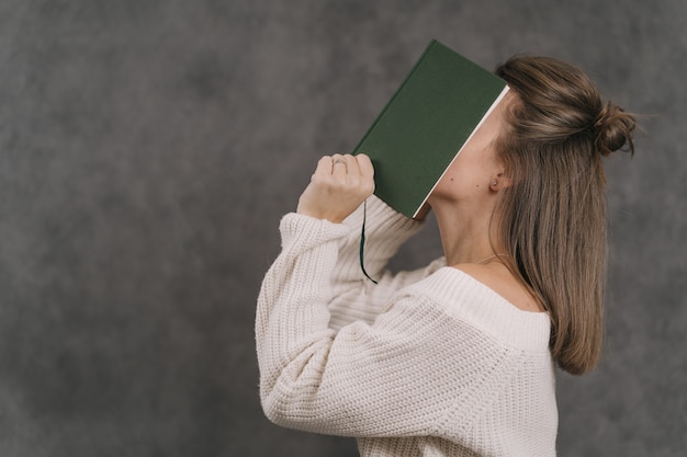 写真 少女は顔を日記で覆っている。女の子は新年の計画を書きます。