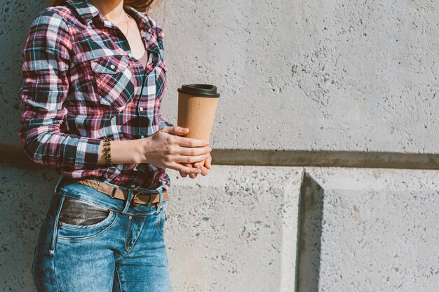Фото Девушка держит в руке термокружку с кофе.