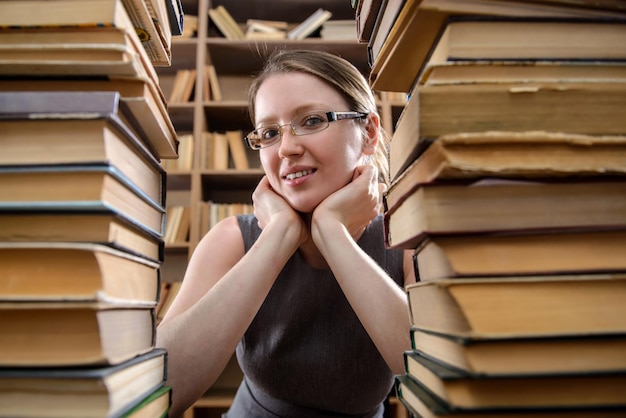 Фото Девушка в очках среди старых книг в библиотеке