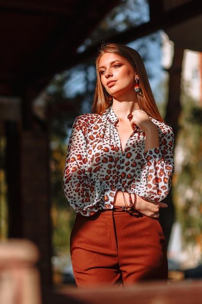 Фото Девушка модель демонстрирует модную верхнюю одежду на улице на веранде летнего кафе одежда для шоу-рума