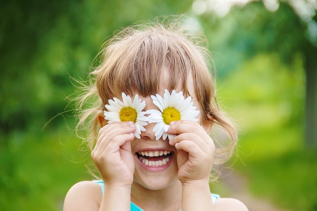 女の子は彼女の手にカモミールの花を持っています。セレクティブフォーカス