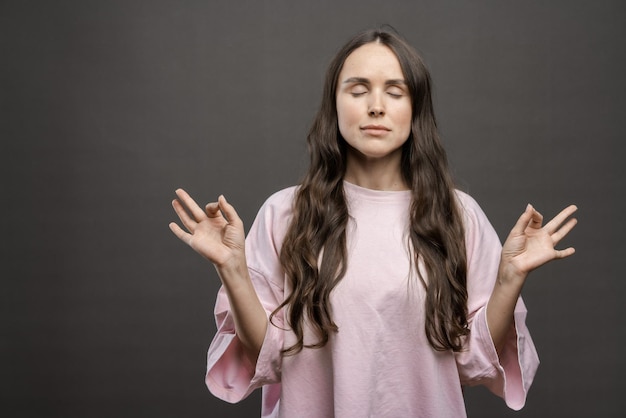 写真 女の子は暗い背景に長い髪のブルネットの女の子を瞑想します