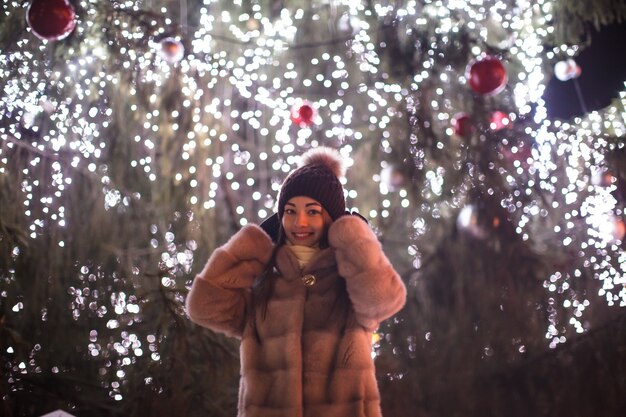 Фото Девушка на улице в новогоднюю ночь закрывает уши от салюта