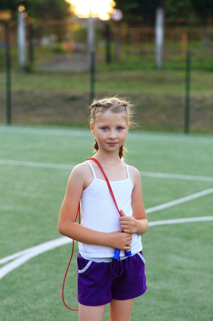 写真 女の子はスポーツグラウンドのより糸に座っています。