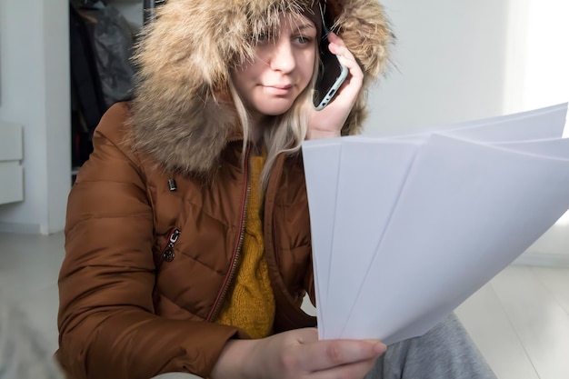 Фото Девушка сидит с купюрами в руках и деньгами в теплой одежде концепция энергетического кризиса
