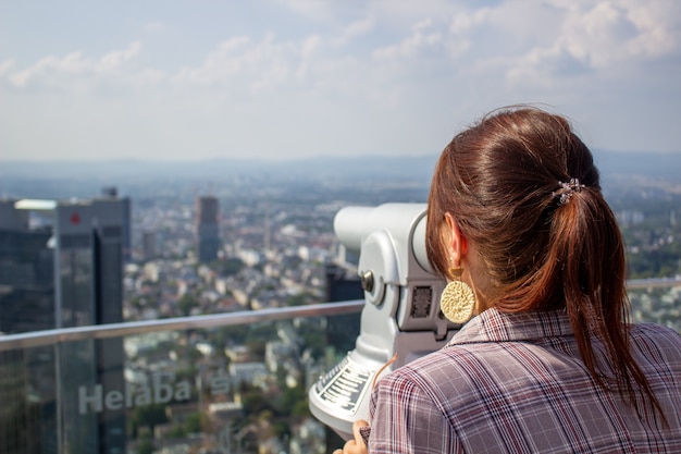 사진 소녀는 마인에있는 프랑크 푸르른의 높은 탑에 서서 도시를 바라 봅니다.