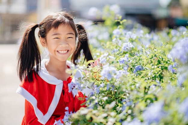 サンディの衣装を着た少女は、笑って、喜んで笑っています。花の中で