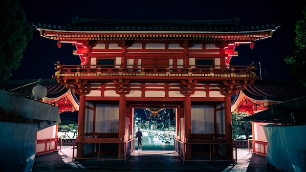 写真 夜は参拝者が集まる八坂神社の門と玄関ビル。祇園は京都で最も有名な神社のひとつです