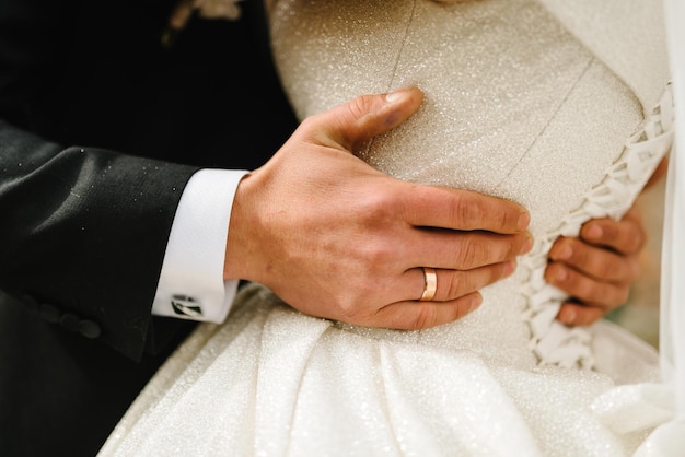 Жених обнимает невесту за талию на природе молодожены вместе обнимаются первая встреча счастливый день свадьбы помолвка крупным планом вид сзади