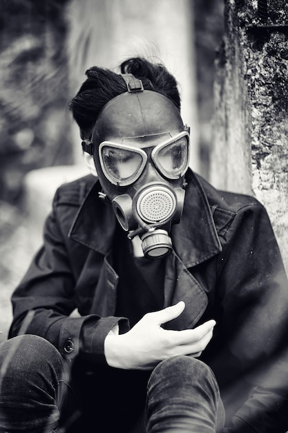 コートと防毒マスクの男。ポスト黙示録的な肖像画アジア人は放射線からマスクされています。その少年はガス中毒のマスクをした韓国人です。アジアのポスト核マスク。
