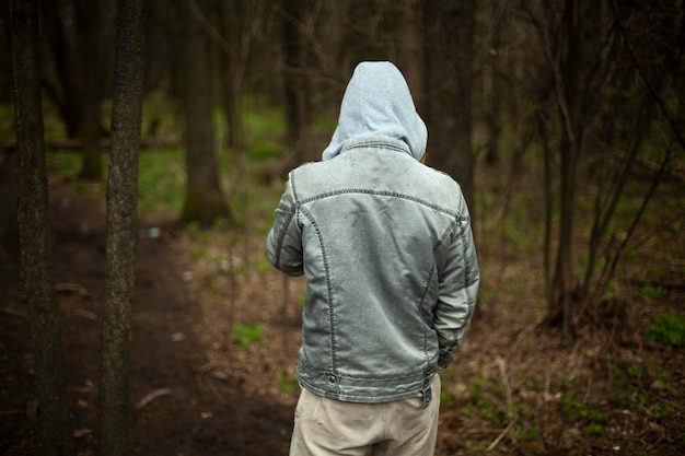 사진 <unk>을 쓴 남자가 뒤에서 꺼져서 청바지를 입은 남자가 숲 속에 서 있습니다.